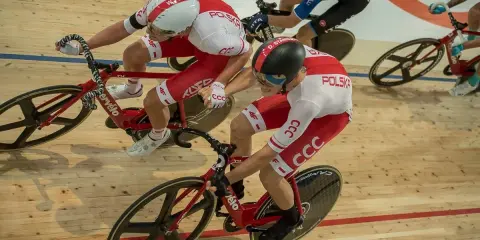 Wyścig kolarski madison. Dwóch kolarzy w biało-czerwonych strojach jedzie na torze.