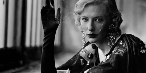A woman with blonde hair and dramatic earrings smokes, a signature element in many Peter Lindbergh famous photos.