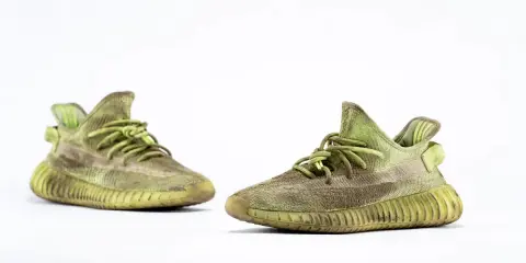 Para zielonych adidas Yeezy 350 z charakterystyczną, prążkowaną podeszwą, gotowe na miejskie przygody.