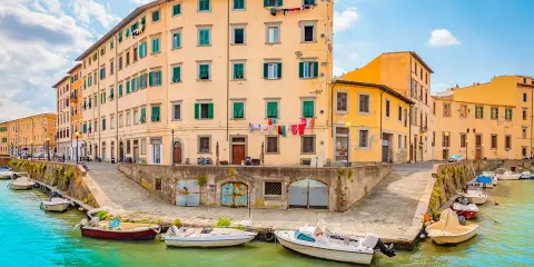 Canali di Livorno, un'idea per cosa vedere a Livorno in un giorno. Case colorate e barche sull'acqua turchese.