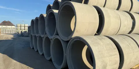 Stos betonu kręgów betonowych do studni, gotowych do budowy podziemnych konstrukcji.