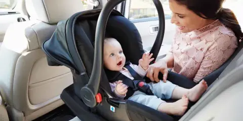 Uśmiechnięta mama patrzy na swoje dziecko w foteliku samochodowym. Ten fotelik dla dziecka do 20 kg zapewnia bezpieczeństwo maluchowi podczas podróży.