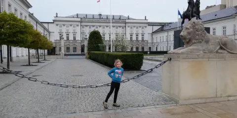 Dziewczynka na trasie traktu królewskiego w Warszawie, obok lwa i pomnika konnego.