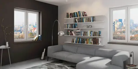 Nowoczesny, biało szary salon aranżacje z szarą kanapą, regałami pełnymi książek i widokiem na miasto.
