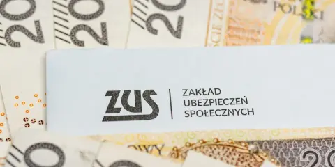 Logo ZUS na tle polskich banknotów 200 zł.