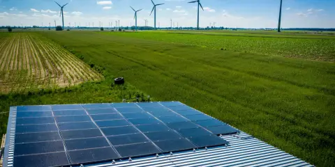 Panele słoneczne na dachu i wiatraki na polu, symbolizujące program agroenergia i zrównoważony rozwój.