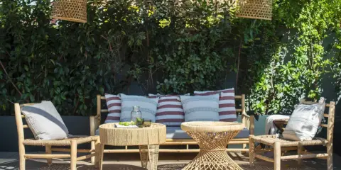Un rincón acogedor para decorar terraza ático. Muebles de ratán, cojines y lámparas de mimbre crean un oasis natural.