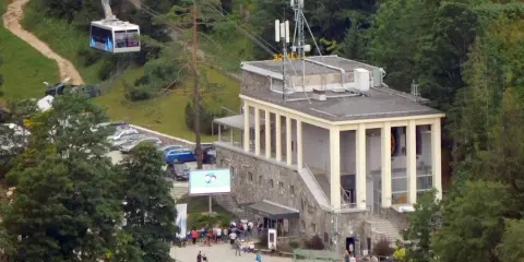 Kolejka linowa nad budynkiem stacji PKL na Kasprowym Wierchu, z widocznymi samochodami i ludźmi.