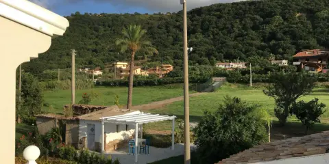 Un angolo di pace tra gli agriturismi in Calabria. Un pergolato bianco con tavolino e sedie blu, circondato da verde e colline rigogliose.