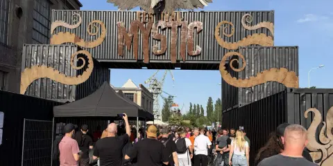 Tłum ludzi wchodzi przez bramę festiwalową "Mystic". To jedno z wielu wydarzeń kulturalnych, takich jak festiwale filmowe w Polsce.