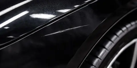 Widoczne na czarnym lakierze samochodu rysy, przypominające hologramy, świadczą o uszkodzeniu powłoki.