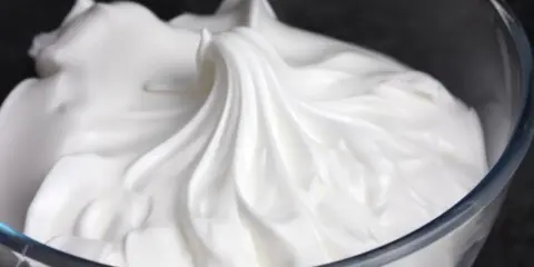 Merengue italiano esponjoso y brillante en un bol de cristal, listo para decorar postres.
