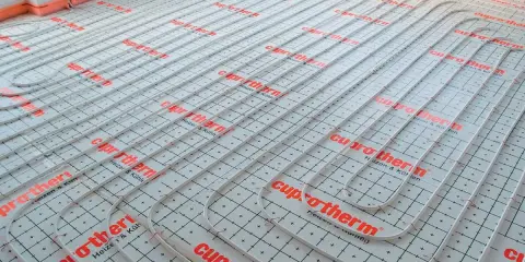 System ogrzewania podłogowego Cuprotherm w trakcie montażu. Wybór między ogrzewaniem podłogowym a grzejnikami to ważna decyzja.