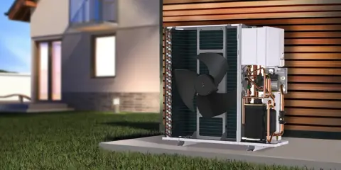 Unidad exterior de bomba de calor para hidrotermia en casa, con ventilador y tuberías de cobre visibles, junto a una casa moderna.
