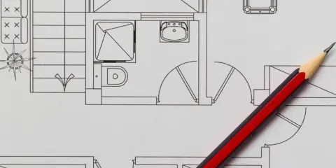 Un crayon rouge et noir sur un plan de maison, idéal pour faire un plan de maison gratuit et visualiser votre projet.
