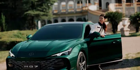 Elegante donna esce dalla MG 7 verde smeraldo, con un palazzo storico sullo sfondo.