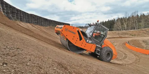 Rodillo Hamm H 20i trabajando en una pendiente, realizando la compactación del suelo.
