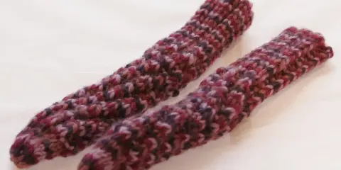 Två handstickade drops spiralsockor i ett melerat garn i vinröda och lila toner.