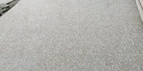 Superficie de hormigón desactivado con pequeñas piedras incrustadas, creando una textura rugosa y antideslizante.