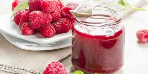 Frische Himbeeren und ein Glas selbstgemachte Himbeermarmelade. Ein einfaches Rezept für den Sommer.