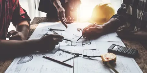 Architetti discutono progetti, cercando soluzioni per sanare un abuso edilizio commesso dal precedente proprietario.