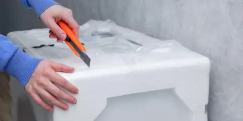 Ręce tnące nożem opakowanie ze styropianu.