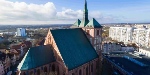 Gotycka katedra z zielonym dachem, otoczona miejską zabudową. Jedna z wielu atrakcji Pomorza Zachodniego.
