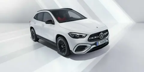 La nuova GLA 2026, un SUV bianco con tetto nero e interni rossi, si presenta in uno studio minimalista.