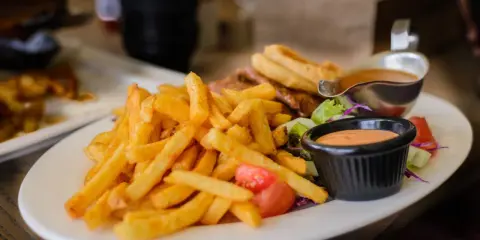 Porcja frytek z sosem i sałatką. Zastanawiasz się, ile kalorii ma porcja frytek?