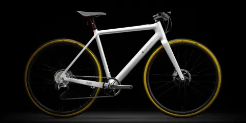 Biały rower elektryczny Eidolon z żółtymi oponami, prezentowany na czarnym tle. To najlżejszy rower elektryczny, który zachwyca minimalistycznym designem.