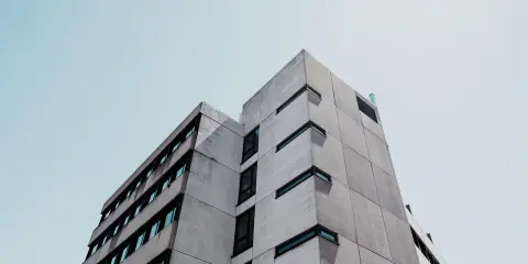 Betonowy budynek o geometrycznej bryle, z rzędami okien. Ta kategoria obiektu budowlanego dominuje w kadrze.