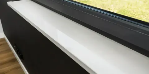 Biały parapet z konglomeratu przy czarnym oknie. Czym czyścić konglomerat, by lśnił jak nowy? Delikatna ściereczka i woda wystarczą.