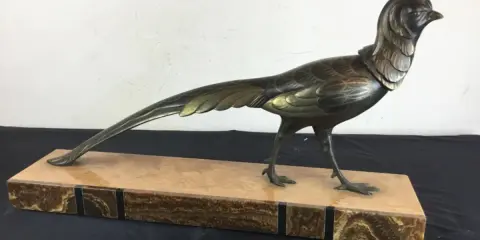 Sculpture d'oiseau en bronze, style Irénée Rochard, sur un socle en marbre veiné. L'oiseau, aux détails fins, arbore une longue queue élégante.