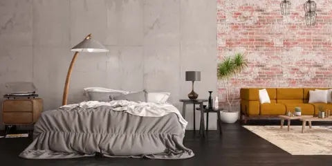 Nowoczesna sypialnia z betonową ścianą i fragmentem z tapetą szara cegła. Wygodne łóżko, kanapa i stylowe lampy tworzą przytulną atmosferę.