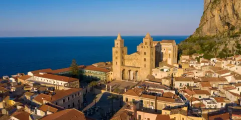 Cefalù cosa vedere: la maestosa Cattedrale Normanna domina il borgo con le sue torri, incastonata tra il mare blu e la rocca imponente.