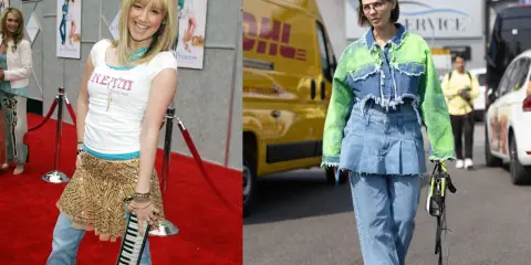 A young woman in a sparkly skirt over jeans poses on a red carpet. Another woman walks in a denim jacket with neon green sleeves, also wearing a skirt over jeans.