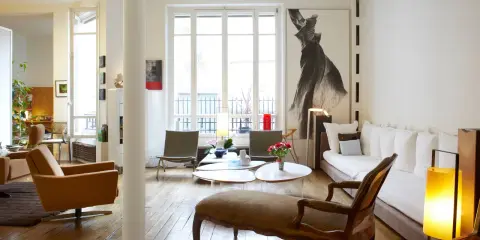 Un salon lumineux où les meubles anciens reviennent à la mode, avec un fauteuil vintage, une méridienne et une grande œuvre d'art.