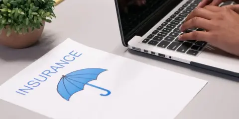 Koniec leasingu a ubezpieczenie: dokument z parasolką i dłonie piszące na laptopie.