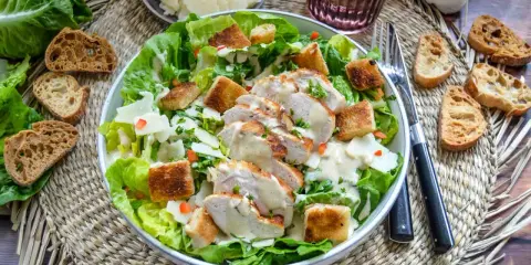 Saftiges Hähnchenbrustfilet auf knackigem Römersalat mit Croutons und cremiger Sauce – eine köstliche Caesar Salad.