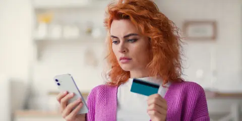Zastanawia się, co to jest dip, przeglądając ofertę w telefonie z kartą w dłoni.