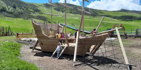 Un grande galeone di legno su un prato verde, perfetto per agriturismi per bambini in Piemonte. Bambini giocano a bordo.