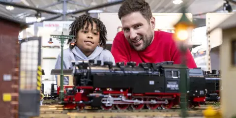 Vater und Sohn bestaunen detailreiche Modelleisenbahnen auf der Modellbaumesse Dortmund.