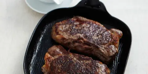 Zwei saftige Rumpsteaks braten in einer Grillpfanne, perfekt gewürzt und bereit zum Genuss.