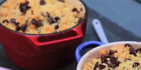 Deux ramequins de crumble pomme banane chocolat, l'un rouge, l'autre bleu, garnis de pépites de chocolat.