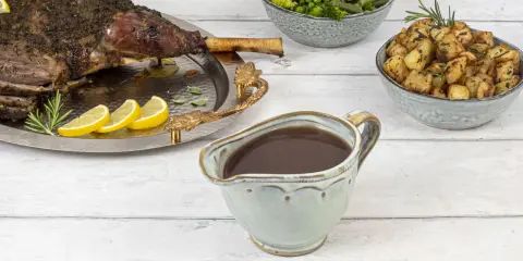 Sauce onctueuse pour accompagner une tranche de gigot d'agneau, avec des pommes de terre rôties et des légumes verts.