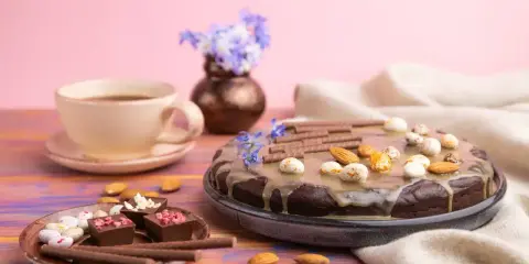 Czekoladowy tort i pralinki na talerzyku, kawa i kwiaty. Idealny przepis na zdrowe słodycze.