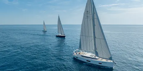 Drei weiße Segelboote segeln auf dem blauen Meer. Die Kosten für ein Segelboot wie dieses sind hoch, aber das Erlebnis unbezahlbar.