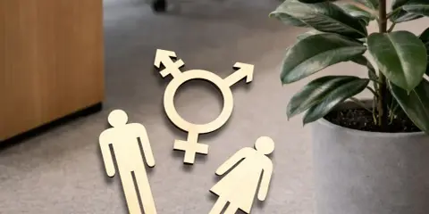 Holzfiguren von Mann, Frau und Transgender-Symbol liegen auf dem Boden. Ein Zeichen für fußgänger gendern.