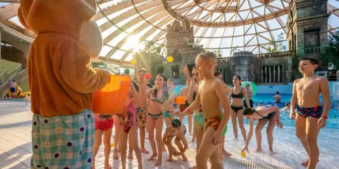 Maskotka rzuca piłeczki dzieciom w aquaparku w Budapeszcie. Radosna zabawa pod szklaną kopułą.
