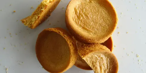 Des morceaux de sablé breton dorés, certains entiers, d'autres brisés, éparpillés sur un fond clair.